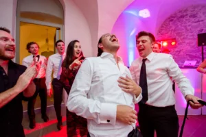 Esküvő fotózás külföldön - Party - vicces színes kép a vőlegényről és barátairól, ahogy leveszik Ricardo nyakkendőjét tánc közben. 2.