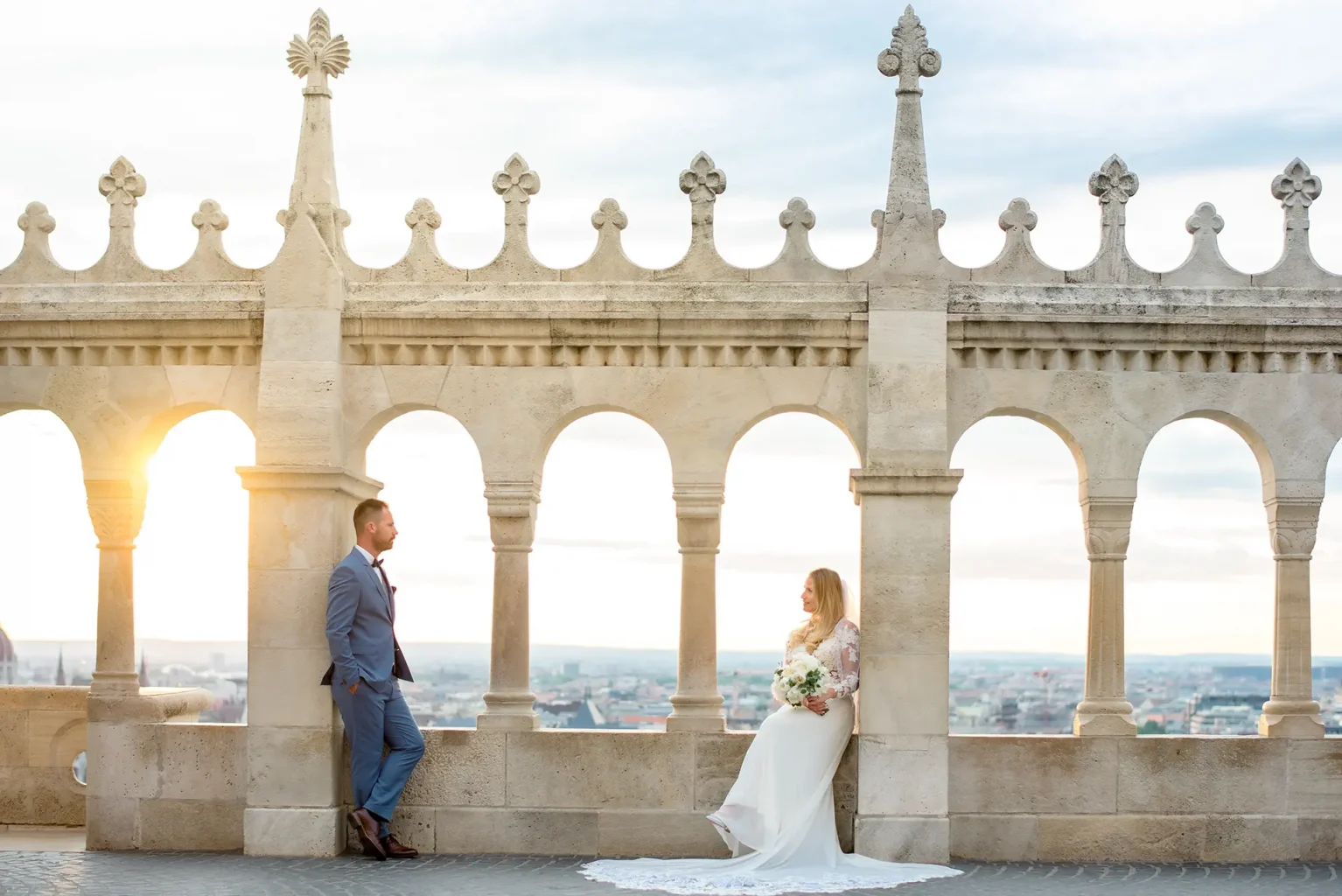 Kreatív fotózás a Halászbástyán - színes - távolabbi esküvői fotó a menyasszonyról és a vőlegényről napfelkeltében - Creative Couple Photoshoot Budapest
