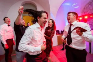 Esküvő fotózás külföldön - Party - vicces színes kép a vőlegényről és barátairól, ahogy leveszik Ricardo nyakkendőjét tánc közben. 3.